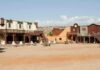 One Man Lives in a Ghost Town A deserted western town with historic buildings under a clear blue sky