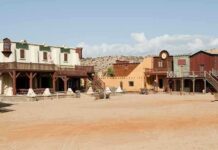 One Man Lives in a Ghost Town A deserted western town with historic buildings under a clear blue sky