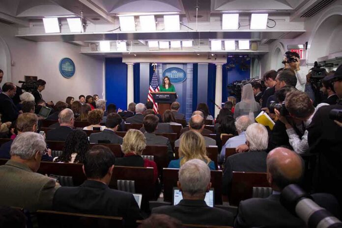 shutterstock_744405130-1 Press secretary at podium addressing reporters in briefing room