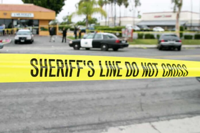 shutterstock_79306801-1 yellow sheriff's line tape blocks a street near police cars