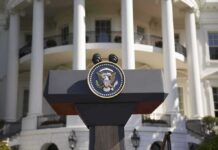 Trump Weighs Firing Ambassador Over $100K Claim Presidential podium with seal in front of white-columned building