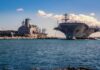 Navy Crew Faces Strain After Months at Sea Aircraft carrier and support ships docked at a naval harbor