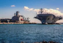 Navy Crew Faces Strain After Months at Sea Aircraft carrier and support ships docked at a naval harbor
