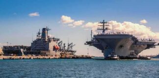 Navy Crew Faces Strain After Months at Sea Aircraft carrier and support ships docked at a naval harbor