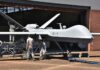 Army Plant to Arm New Attack Drones Military drone being serviced by ground crew outside a hangar