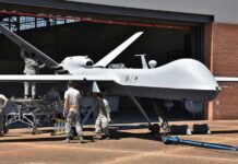 Army Plant to Arm New Attack Drones Military drone being serviced by ground crew outside a hangar