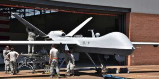 Army Plant to Arm New Attack Drones Military drone being serviced by ground crew outside a hangar