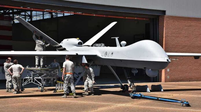 shutterstock_1079246960-1 Military drone being serviced by ground crew outside a hangar