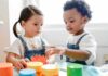 Governor Debate Turns to Migrant Child Care Toddlers playing with colorful stacking cups at a table