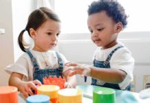 Governor Debate Turns to Migrant Child Care Toddlers playing with colorful stacking cups at a table