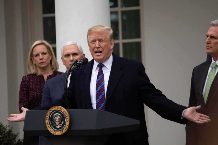 shutterstock_1276349389 Donald Trump speaks at a podium with Mike Pence and Kevin McCarthy nearby