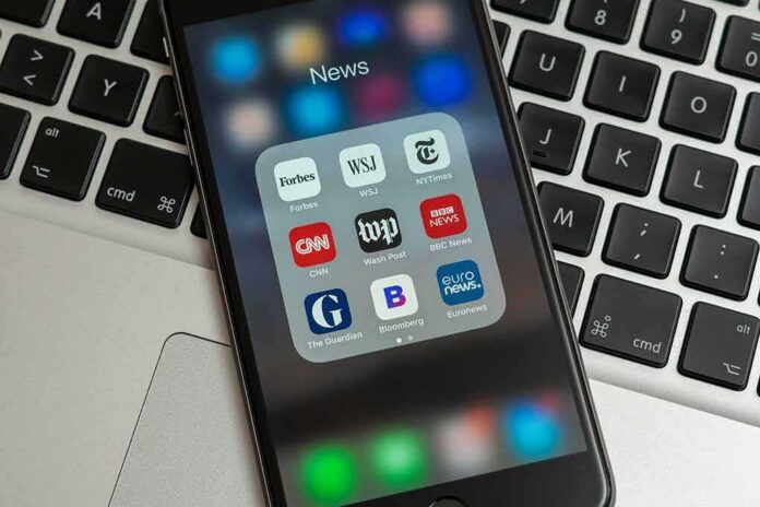 Smartphone displaying a folder of news apps on a laptop keyboard