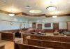 Woman Pleads Guilty to Marriage Fraud Empty courtroom with wooden benches and judge's bench