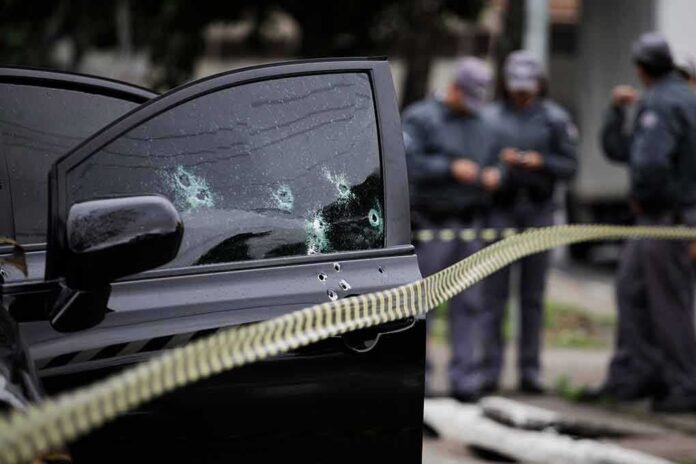 shutterstock_1357161179 Car door with bullet holes at a taped-off crime scene