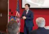 Minnesota Defends Its Immigration Policies Speaker in a navy suit addressing an audience at a podium