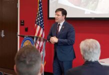 Minnesota Defends Its Immigration Policies Speaker in a navy suit addressing an audience at a podium