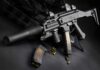 The Israeli Gun That Became a Global Icon Submachine gun with suppressor and magazines on dark surface