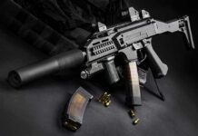 Submachine gun with suppressor and magazines on dark surface