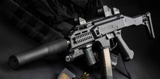 The Israeli Gun That Became a Global Icon Submachine gun with suppressor and magazines on dark surface