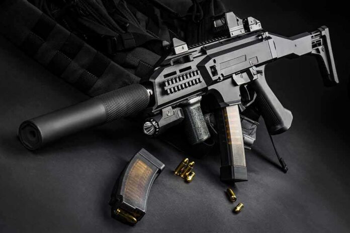 Submachine gun with suppressor and magazines on dark surface