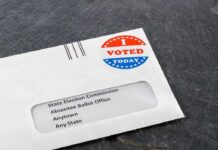 Utah Official Raises Alarm Over Voter Data Absentee ballot envelope with I Voted sticker on dark surface
