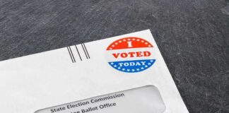 Utah Official Raises Alarm Over Voter Data Absentee ballot envelope with I Voted sticker on dark surface
