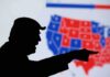 silhouetted person pointing in front of a U.S. election map