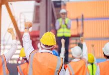 Missing Bosses, Unpaid Wages Fuel Worker Anger construction workers raising fists during a safety briefing