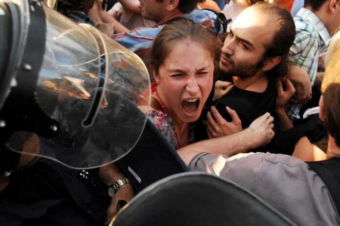 shutterstock_192867317 Protesters clash with riot police as woman shouts