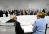 Trump’s Iran Threat Raises Tensions Angela Merkel and Narendra Modi seated at a large round table during an international summit