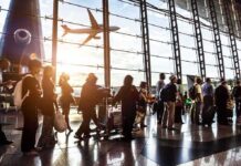Lands In U.S.? Brazil Travel Ban Sparks Controversy Passengers queue inside an airport terminal at sunset