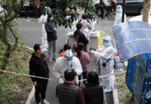 Chemical Leak Triggers Toledo Evacuations Christian Jones and others wait at an outdoor COVID-19 testing site with staff in protective suits