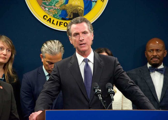 shutterstock_2257605487 Gavin Newsom speaks at a podium with microphones during a press conference