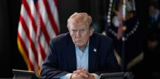 Trump Shifts Ads to Private Funding Donald Trump seated at a table between two desk phones