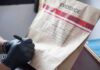 Gloved hands labeling a sealed evidence bag